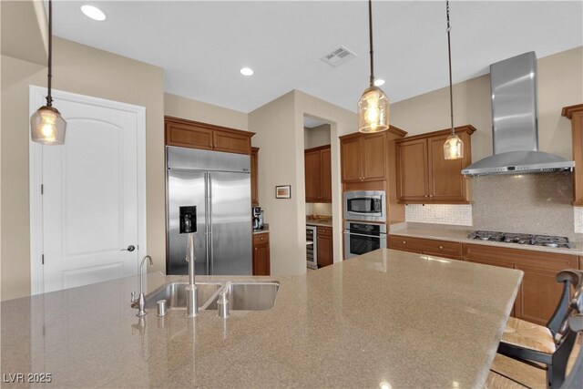 kitchen with visible vents, built in appliances, wall chimney range hood, a sink, and backsplash