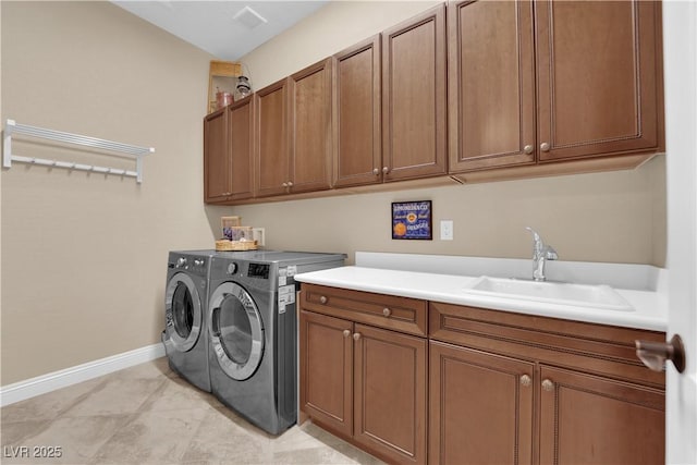 laundry area with baseboards, a sink, cabinet space, independent washer and dryer, and light tile patterned floors