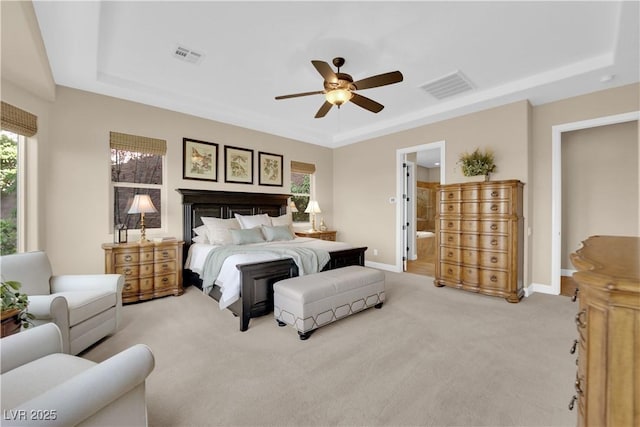 bedroom with light carpet, a tray ceiling, and visible vents