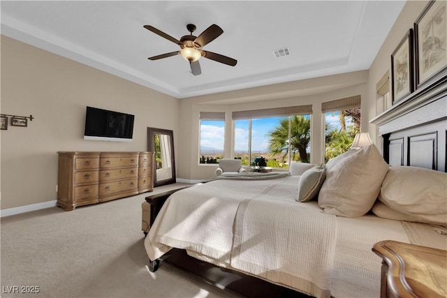 bedroom with ceiling fan, carpet floors, baseboards, a tray ceiling, and visible vents