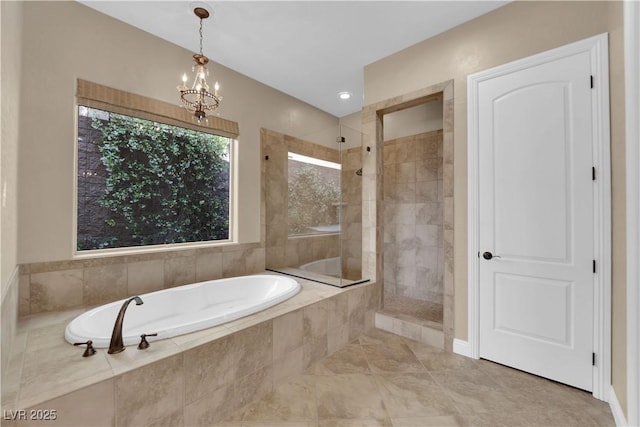 bathroom with walk in shower, an inviting chandelier, and a garden tub