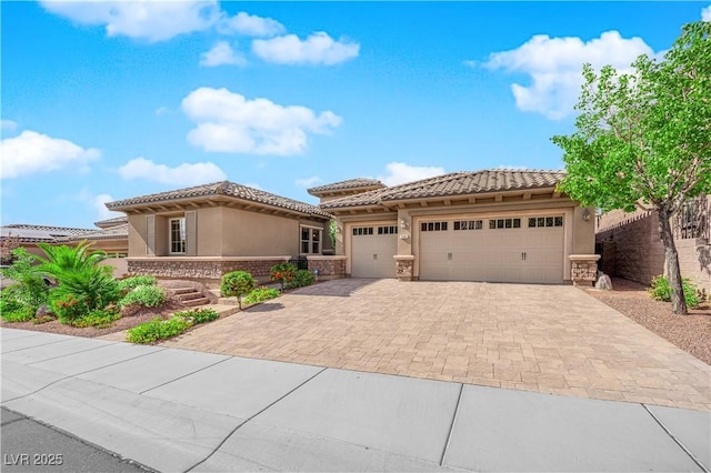 view of front facade featuring a garage, stone siding, decorative driveway, stucco siding, and a tile roof