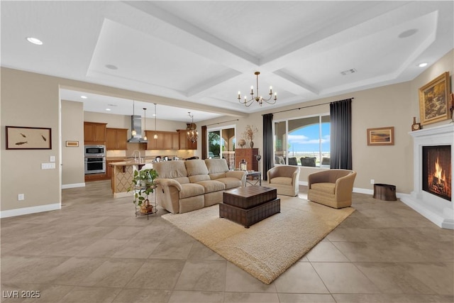 living area with beam ceiling, a chandelier, baseboards, a lit fireplace, and coffered ceiling
