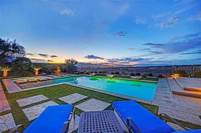 pool at dusk featuring a fenced backyard and a fenced in pool
