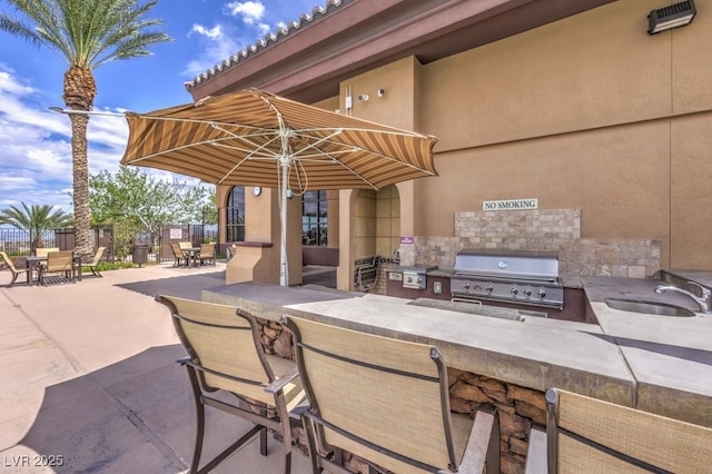 view of patio / terrace featuring fence, outdoor wet bar, exterior kitchen, area for grilling, and a sink