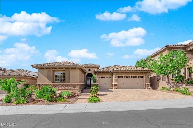 mediterranean / spanish house with stucco siding, an attached garage, driveway, and stone siding