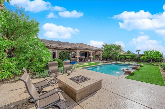 outdoor pool with a patio area and an outdoor fire pit