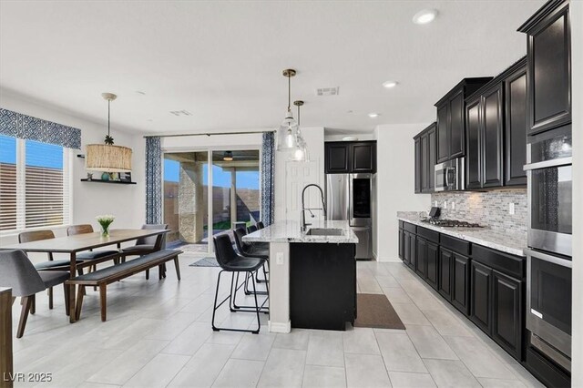3136 Mossfield Ave, Henderson, NV 89052 - kitchen featuring stainless steel appliances, dark cabinetry, tasteful backsplash, light stone countertops, and recessed lighting