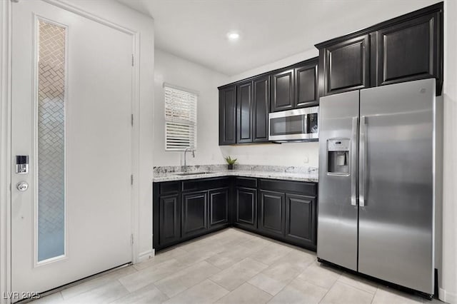 3136 Mossfield Ave, Henderson, NV 89052 - kitchen with stainless steel appliances, dark cabinetry, light stone counters, recessed lighting, and light tile patterned floors