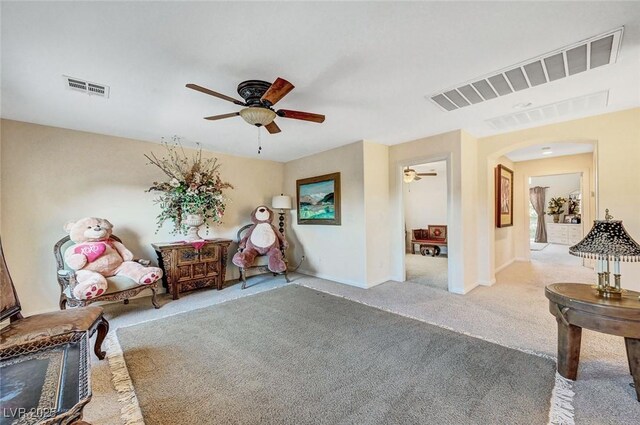 sitting room featuring arched walkways, a ceiling fan, carpet flooring, and visible vents