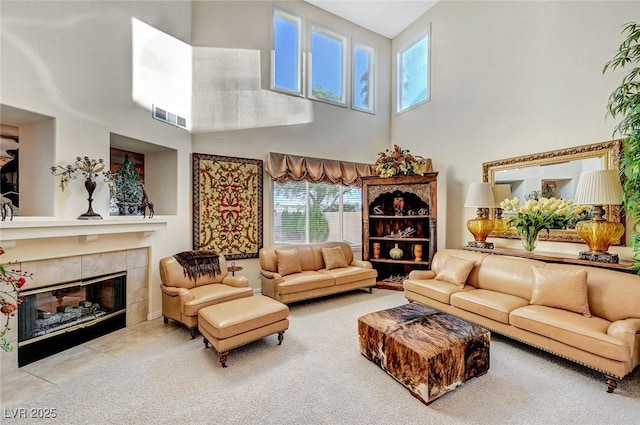 carpeted living area with visible vents, a high ceiling, and a fireplace
