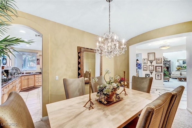 dining space featuring arched walkways, a notable chandelier, and light carpet