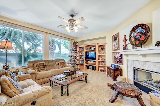 living room with carpet floors, ceiling fan, and a tile fireplace