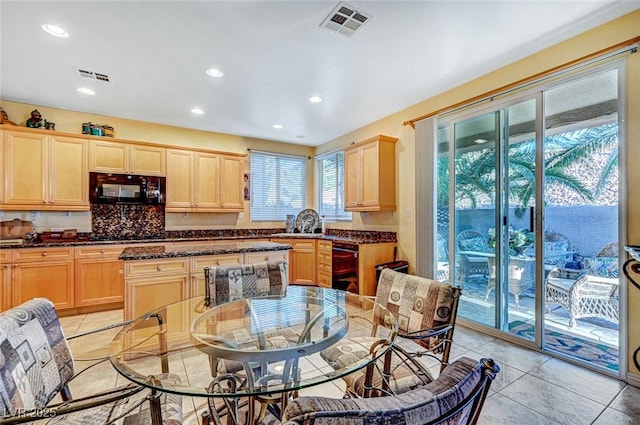 kitchen with light brown cabinets, black appliances, and visible vents
