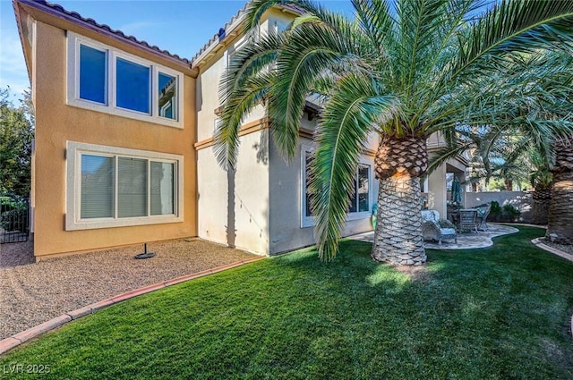 rear view of house with a patio, stucco siding, a yard, and fence
