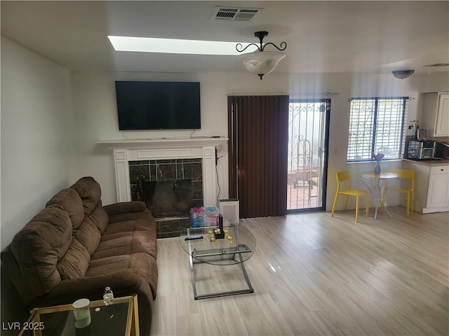 3164 Elmrock Pl, Las Vegas, NV 89121 - living room featuring visible vents, wood finished floors, a tiled fireplace, and a skylight