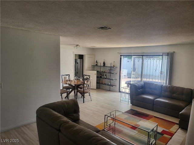 3164 Elmrock Pl, Las Vegas, NV 89121 - living room with light wood finished floors, a textured ceiling, and visible vents