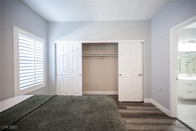 bedroom with a closet, dark wood finished floors, baseboards, and multiple windows