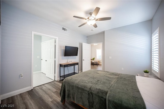bedroom with visible vents, baseboards, wood finished floors, and multiple windows