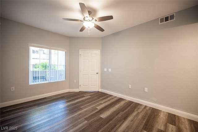 empty room with visible vents, baseboards, ceiling fan, and dark wood-style floors