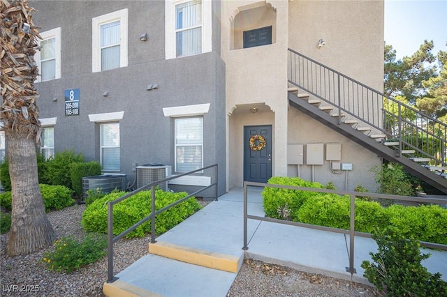 entrance to property featuring central AC and stucco siding