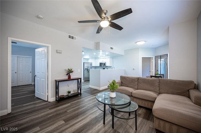 living area featuring dark wood-style flooring, ceiling fan, visible vents, and baseboards