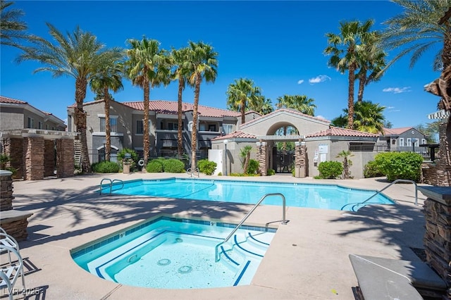 pool with fence, a community hot tub, and a patio area