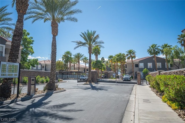 view of street featuring a residential view, sidewalks, a gated entry, curbs, and a gate
