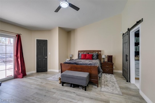 bedroom featuring access to outside, ceiling fan, a barn door, baseboards, and light wood-type flooring