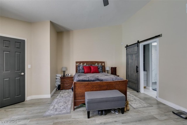 bedroom with baseboards, a barn door, and light wood finished floors