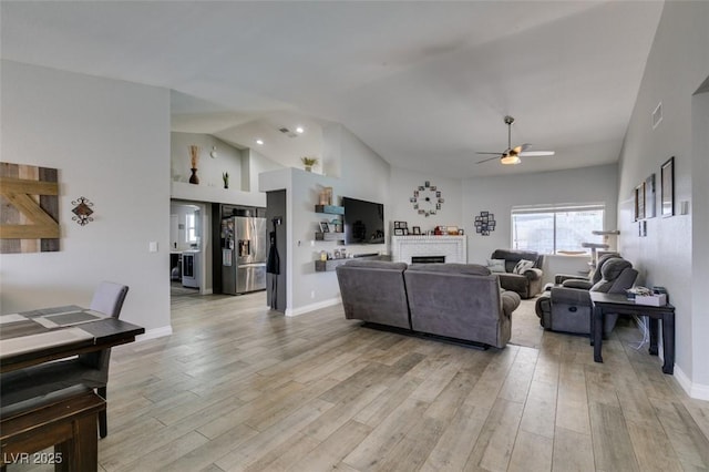 living area featuring a ceiling fan, visible vents, light wood finished floors, and a fireplace