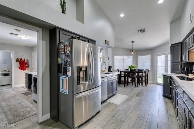 kitchen featuring visible vents, light wood-type flooring, light countertops, baseboards, and stainless steel appliances