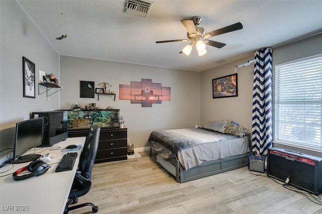 bedroom with ceiling fan, multiple windows, wood finished floors, and visible vents