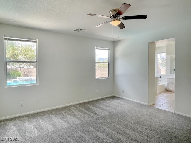 empty room with a ceiling fan, baseboards, light colored carpet, and a wealth of natural light