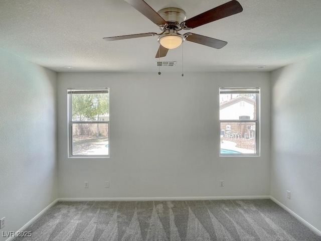 carpeted spare room featuring a healthy amount of sunlight, baseboards, and visible vents