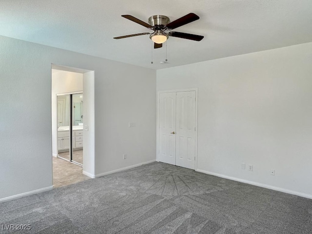 carpeted empty room with baseboards and a ceiling fan
