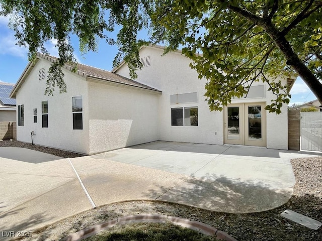 rear view of house with fence, french doors, a patio area, and stucco siding