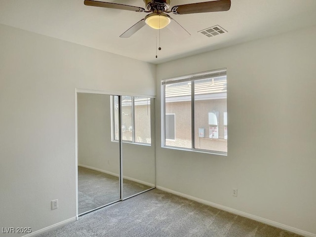 unfurnished bedroom featuring ceiling fan, carpet floors, baseboards, visible vents, and a closet