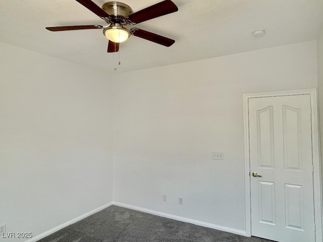 empty room featuring dark colored carpet, a ceiling fan, and baseboards