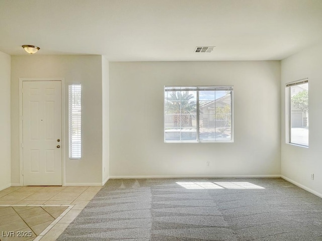 foyer entrance featuring visible vents, baseboards, light tile patterned flooring, and light colored carpet