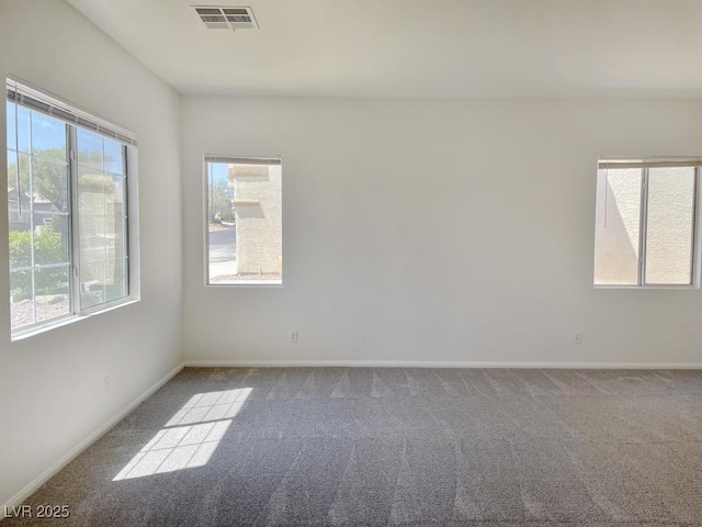empty room featuring visible vents, carpet, baseboards, and a wealth of natural light