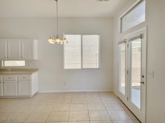 unfurnished dining area featuring light tile patterned floors, baseboards, visible vents, and a chandelier