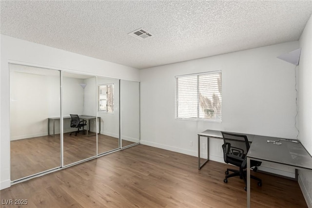 office featuring visible vents, baseboards, a textured ceiling, and wood finished floors