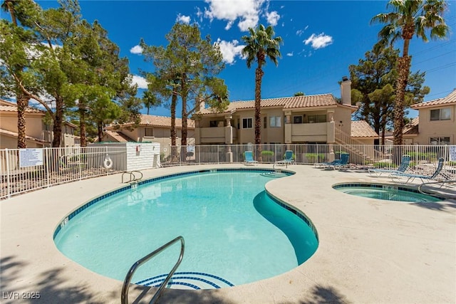 pool with fence, a hot tub, and a patio area