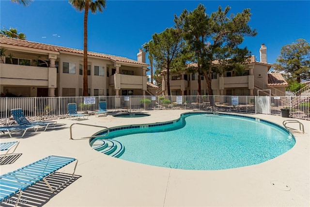 pool with a community hot tub, a patio area, and fence