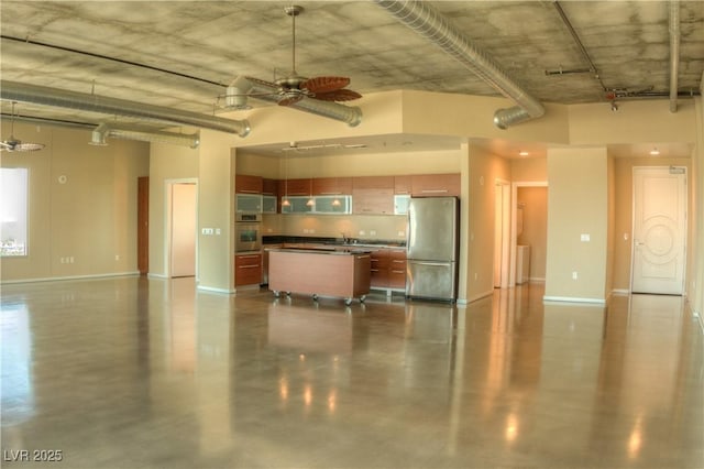interior space with a sink, baseboards, ceiling fan, and freestanding refrigerator