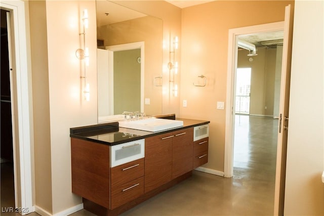 bathroom featuring vanity, baseboards, and finished concrete floors