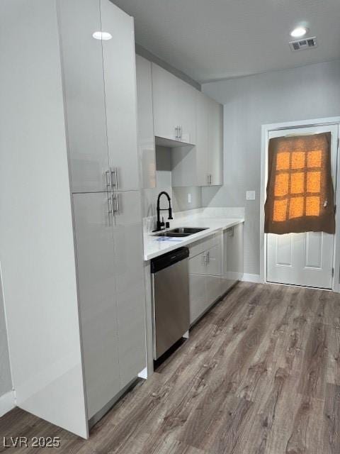 kitchen featuring stainless steel dishwasher, light countertops, white cabinetry, and light wood-style floors