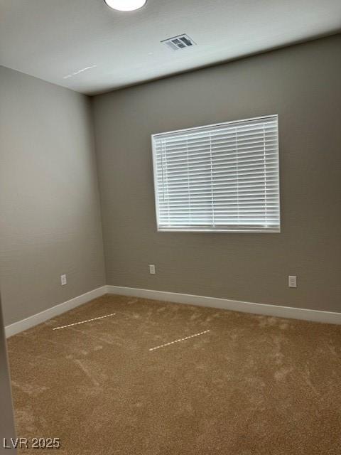 empty room featuring baseboards, visible vents, and light colored carpet