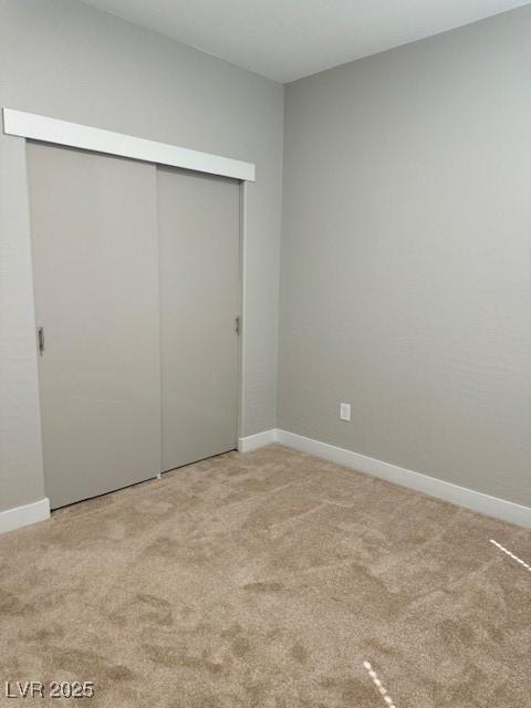 unfurnished bedroom featuring carpet floors, baseboards, and a closet
